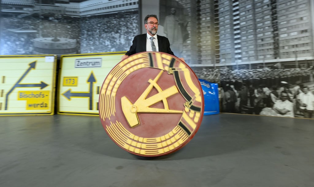 Auktionator Stefan Günther rollt ein 1,20 Meter großes DDR-Emblem durch das DDR-Museum im Simmel Markt am Albertplatz.