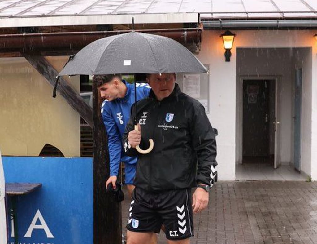 Findet Schutz unter einem Regenschirm: FCM-Cheftrainer Christian Titz. Hinter ihm huscht Daniel Elfadli in den Bus zurück.