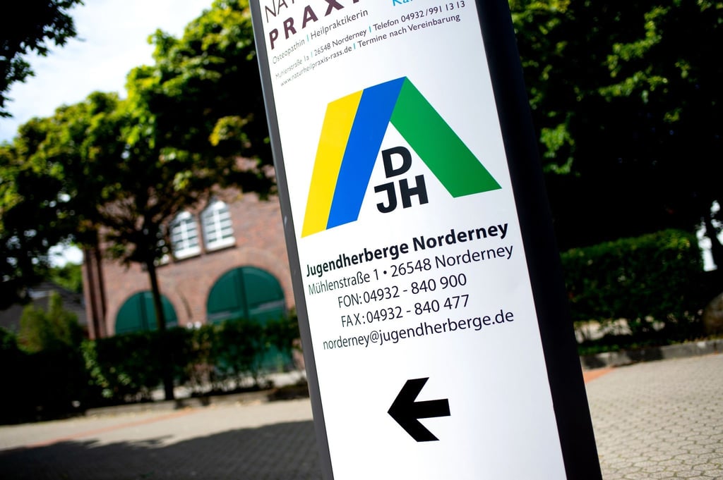 Ein Schild mit dem Logo des DJH steht vor einer Jugendherberge im Norderney.