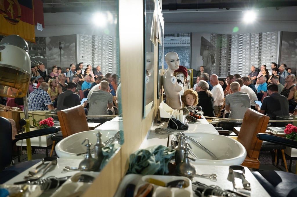 Teilnehmende stehen und sitzen in den Ausstellungsräumen des bereits geschlossenen Museums „Welt der DDR“.