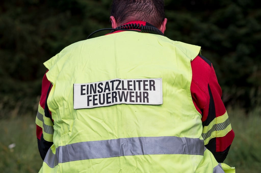 Ein Einsatzleiter der Feuerwehr sitzt an der zentralen Sammelstelle nach einem Waldbrand.