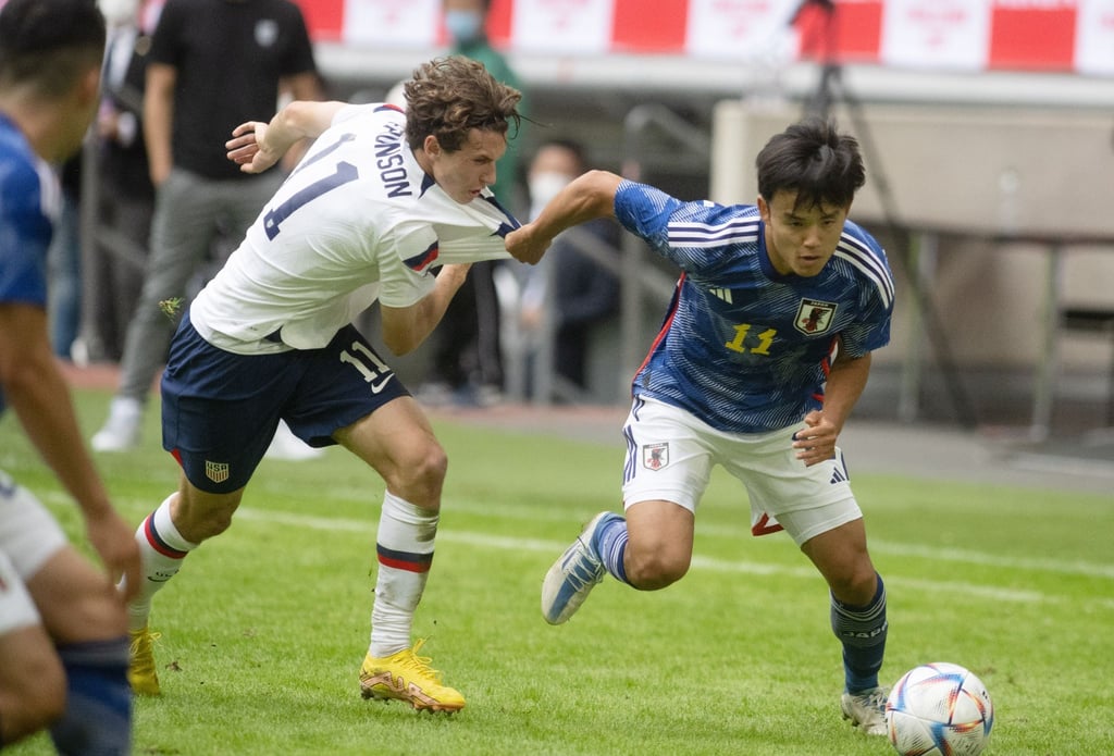 Japans Kubo Takefusa (r) und Brenden Aaronson aus den USA versuchen an den Ball zu kommen.