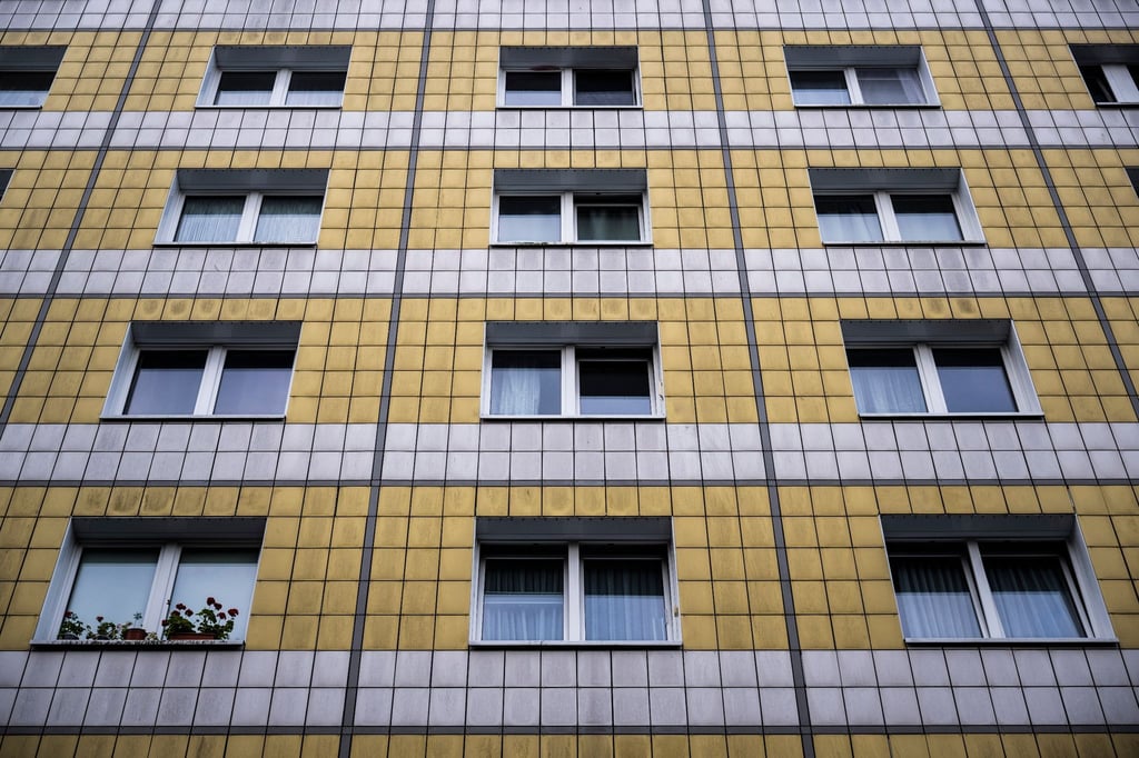 An einer gelb-weißen Hausfassade sind Fenster wie ein Muster angeordnet.