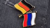 Ein Mann trägt einen Anstecker mit einer kleinen deutschen und einer russischen Flagge an seinem Sakko.
