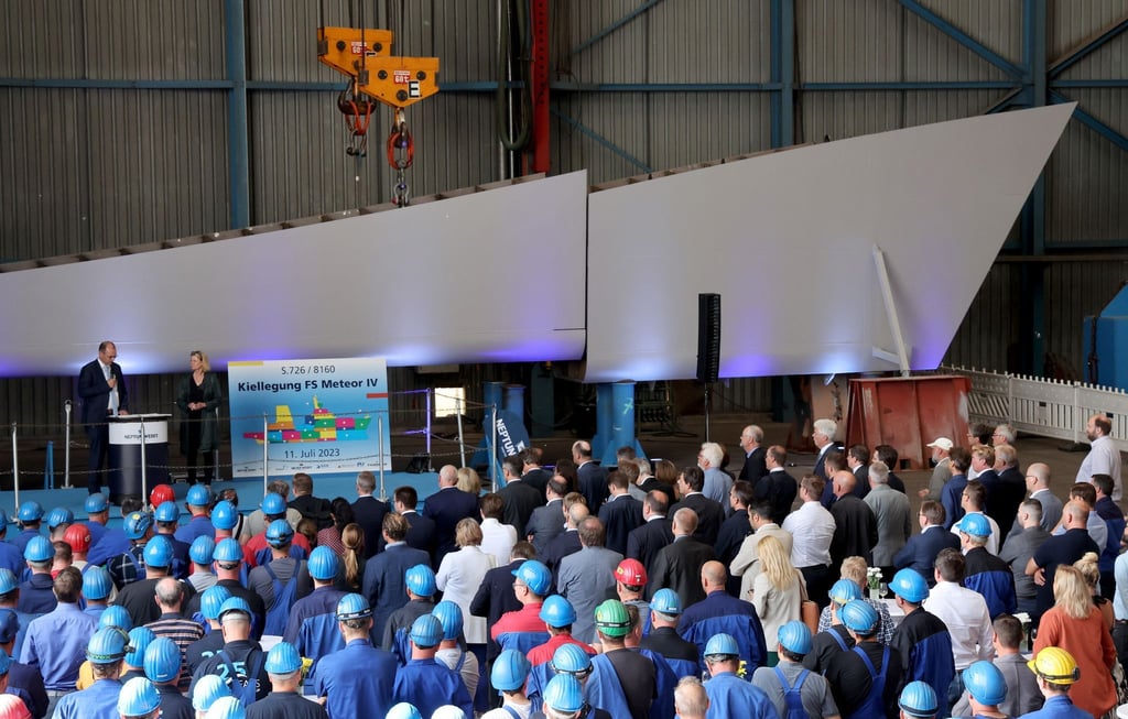 Werftarbeiter verfolgen auf der Neptun Werft die Kiellegung des Forschungsschiffes "Meteor IV".