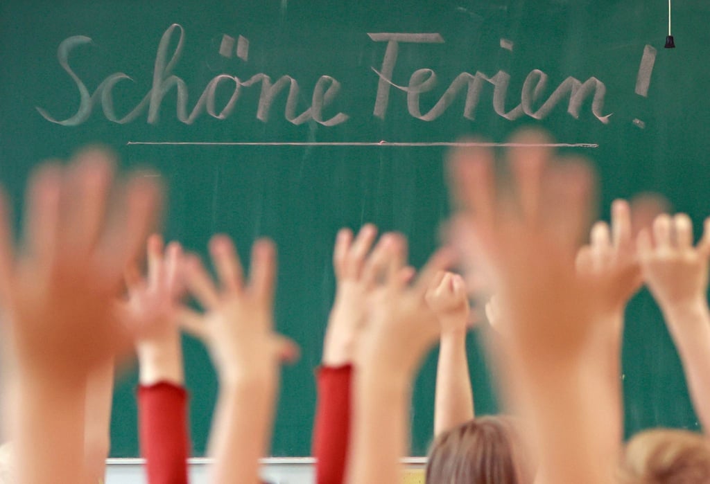 Schülerinnen und Schüler einer ersten Klasse freuen sich in ihrem Klassenraum auf die Sommerferien.