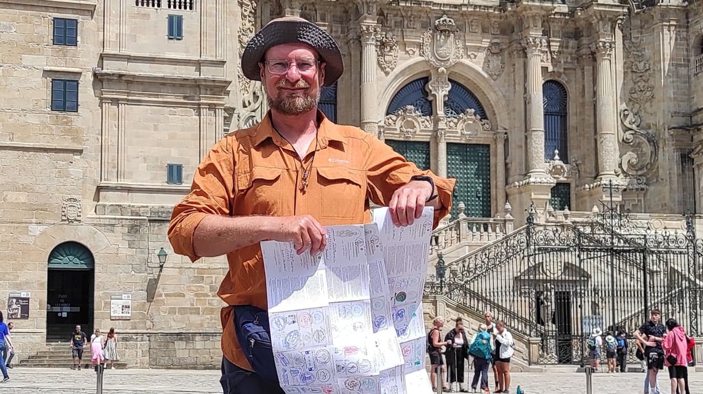 Marcin-Jan Franke zeigt seine Stempelkarten vor der Kathedrale in Santiago de Compostela.