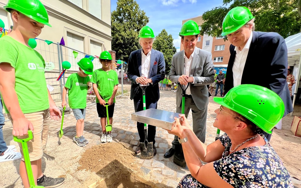 Marion Stellfeld (rechts) legt mit John (links), Ben und Calvin sowie Günther Engler, Georg Faltbaum und Maik Grawenhoff den Grundstein.