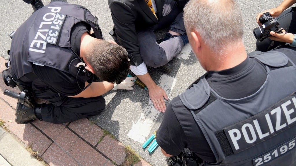 Ein Klimaaktivist hat sich mit der Handfläche am Asphalt festgeklebt.