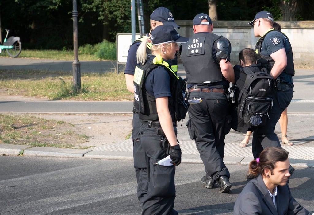 Die Polizei trägt einen Aktivisten der Gruppe Letzte Generation weg, der mit anderen die Fahrbahnen rund um die Siegessäule in Berlin blockiert hat.