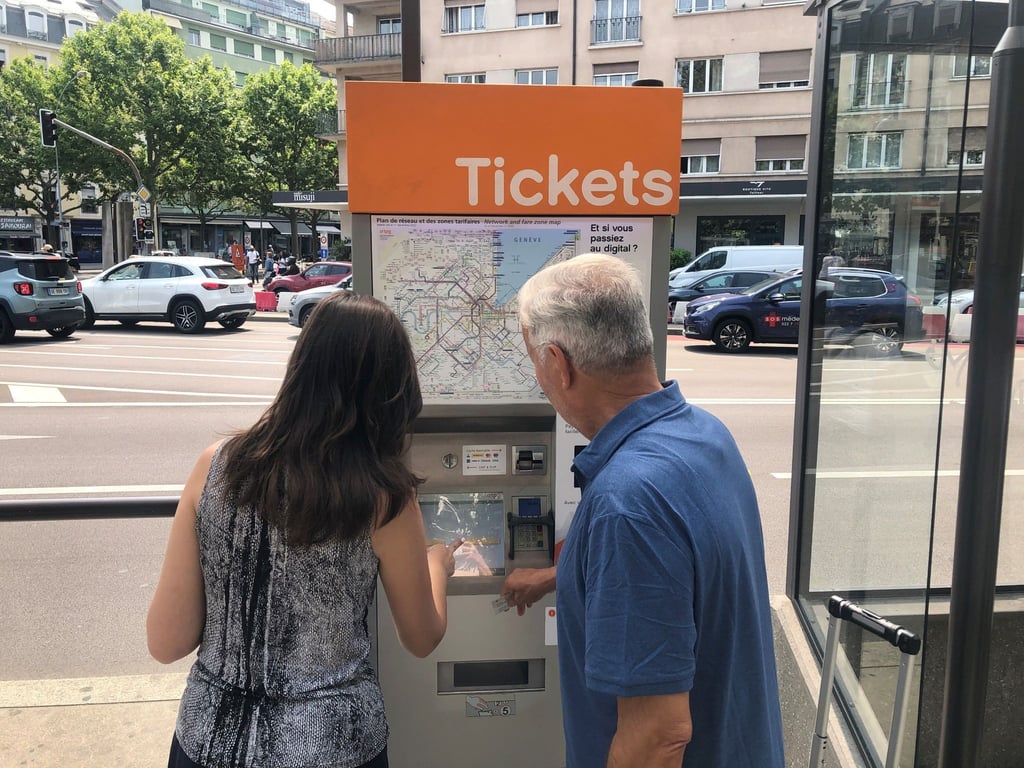 Zwei Leute versuchen, an einem Ticket-Automaten in Genf Fahrkarten zu erwerben.