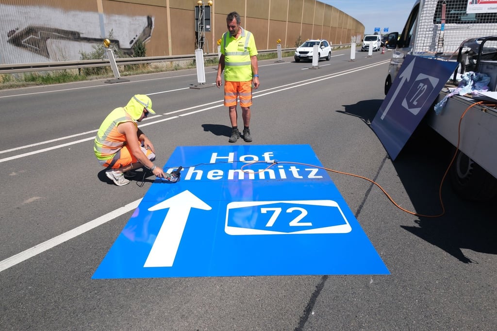 Mitarbeiter einer Straßenmeisterei arbeiten an einem Schild zur Autobahn A72.