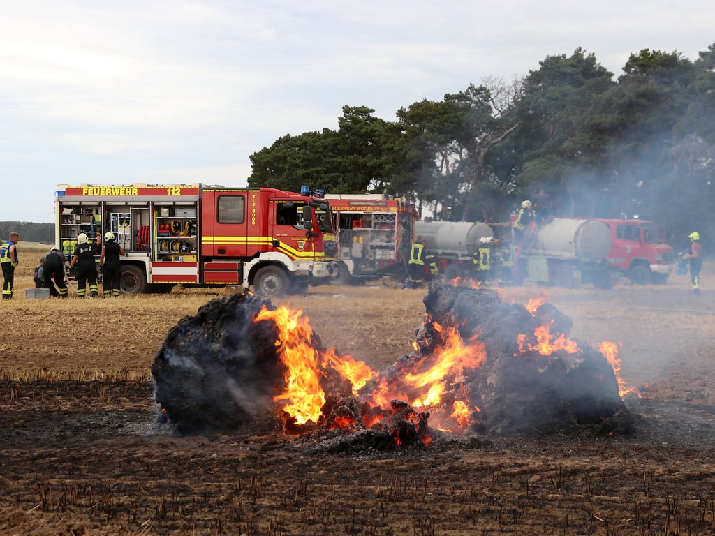 Feuerwehrleute und Landwirte aus der Region Burg arbeiteten zwischen Stegelitz und Tryppehna zusammen. Im Vordergrund ein brennender Strohballen.