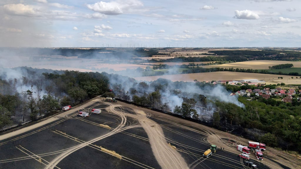 Einsatzkräfte der Feuerwehr löschen entlang eines abgebrannten Feldes einen Waldbrand. Der Brand der 15 Hektar großen landwirtschaftlichen Nutzfläche zwischen den Orten Markröhlitz und Eulau im Burgenlandkreis ist gelöscht.