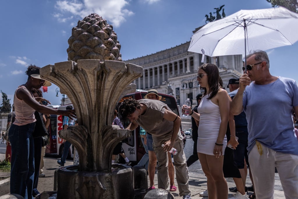 Schirm als Schutz: Touristen in der sengenden Sonne auf der Piazza Venezia in Rom.