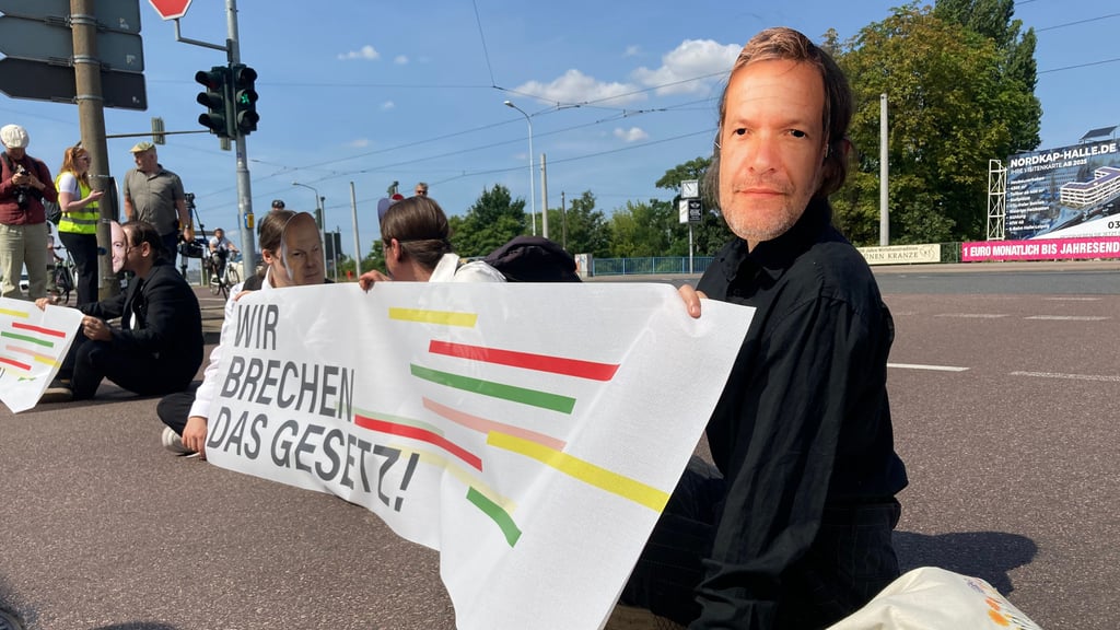 Erst später klebte sich ein Mitglied der „Letzten Generation“ (r.) mit der Hand auf die Straße.