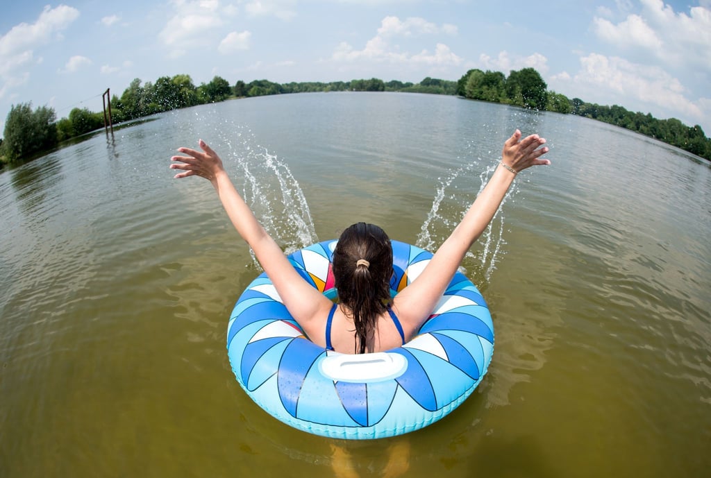 Eine junge Frau badet mit einem Schwimmreifen in einem See.