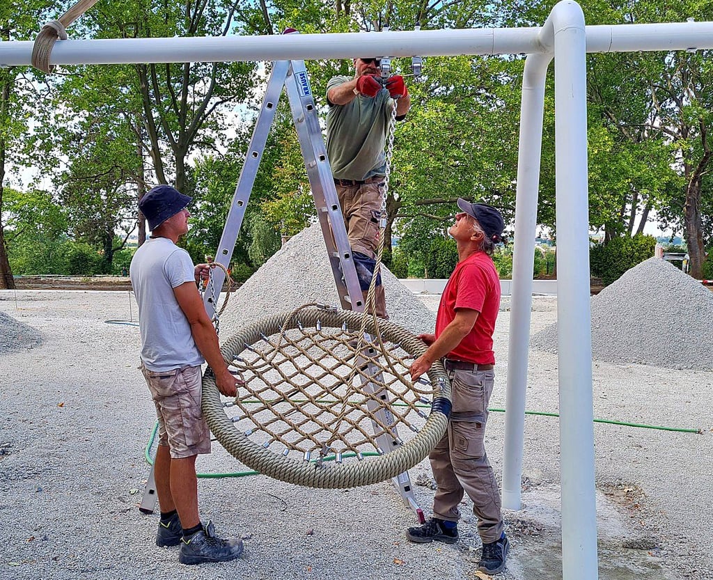 Installation einer Nestschaukel auf dem neuen Spielplatz.