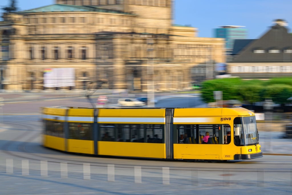 Eine Straßenbahn der Dresdner Verkehrsbetriebe (DVB) fährt am Morgen in der Altstadt über den Theaterplatz an der Semperoper entlang.
