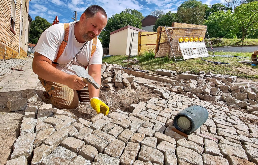 Enrico Rabe verlegt in Beyernaumburg mit den alten Granitsteinen das neue Pflaster am Steinberg.