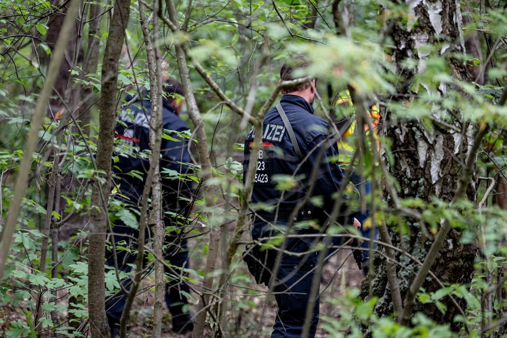 Polizisten laufen im Bereich der südlichen Landesgrenze von Berlin durch Unterholz.
