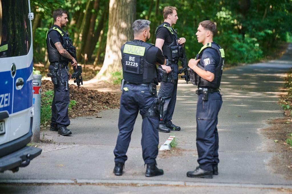 Polizisten stehen am Eingang eines Waldgebietes.