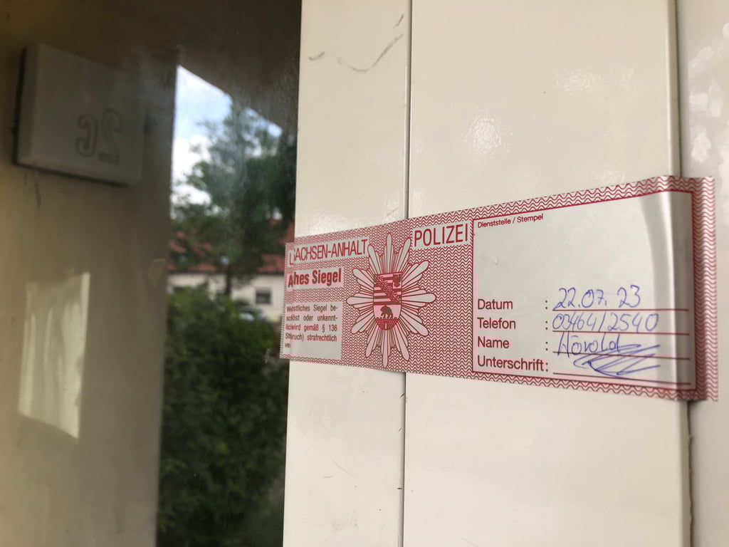 Nach dem Brand in der Straße der Volkssolidarität in Sangerhausen ist die Eingangstür polizeilich versiegelt.