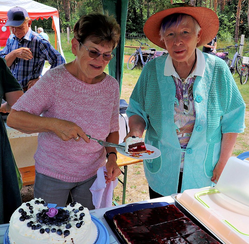 Elfie Schmidt (li.) hat die von Ute Braune (re.) gebackene Sahnetorte mit Heidelbeeren und Kirschen aufgeschnitten.