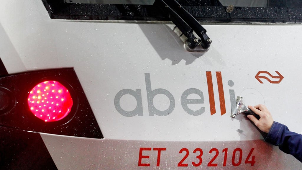 Ein Mitarbeiter der DB-Regio entfernt von einem Nahverkehrszug den Schriftzug "Abellio".