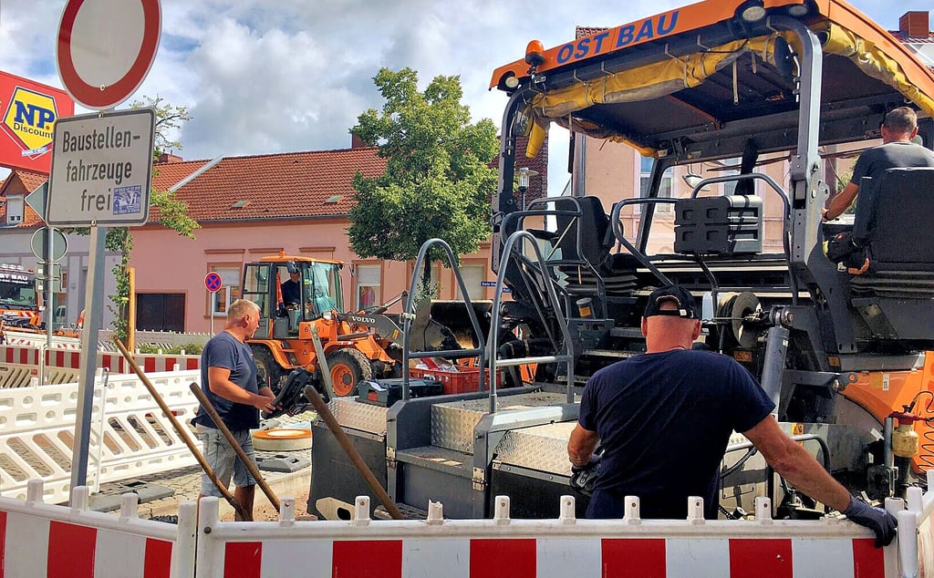 Ost-Bau-Vorarbeiter Andreas Barfuß (links) bedient die Maschine, in Windeseile wird die erste Schicht in der Breiten Straße in Osterburg zur Einmündung Golle aufgetragen. Es folgt der Binder.