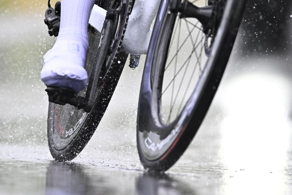 Ein Radfahrer fährt bei Regen über eine Straße.