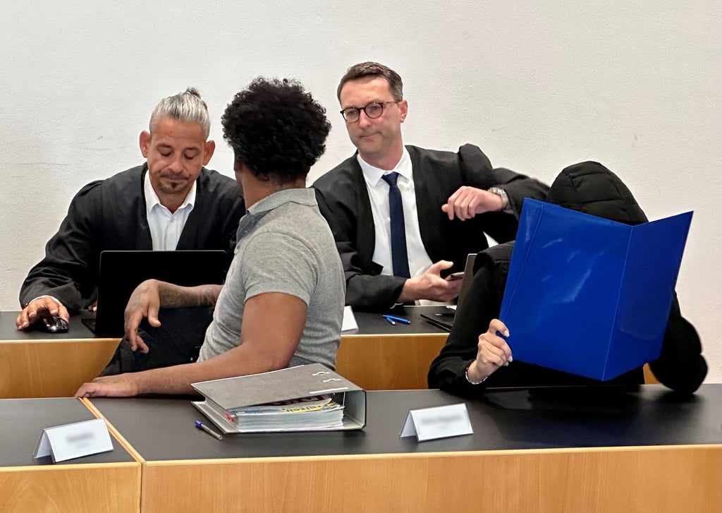 Eine ehemalige Justizvollzugsbeamtin (vorn r) und ein Häftling der Justizvollzugsanstalt Kaisheim (vorn l) sitzen auf der Anklagebank im Strafjustizzentrum Augsburg, im Hintergrund die Strafverteidiger.