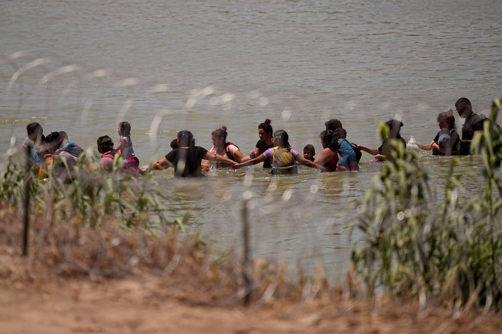 Migranten überqueren Hand in Hand den Fluss Rio Grande zwischen Mexiko und den USA.