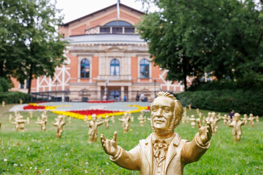 Goldfarbene Wagner-Figuren des Konzeptkünstler Ottmar Hörl stehen im Rahmen der Kunstinstallation „You're welcome“ vor dem Festspielhaus.