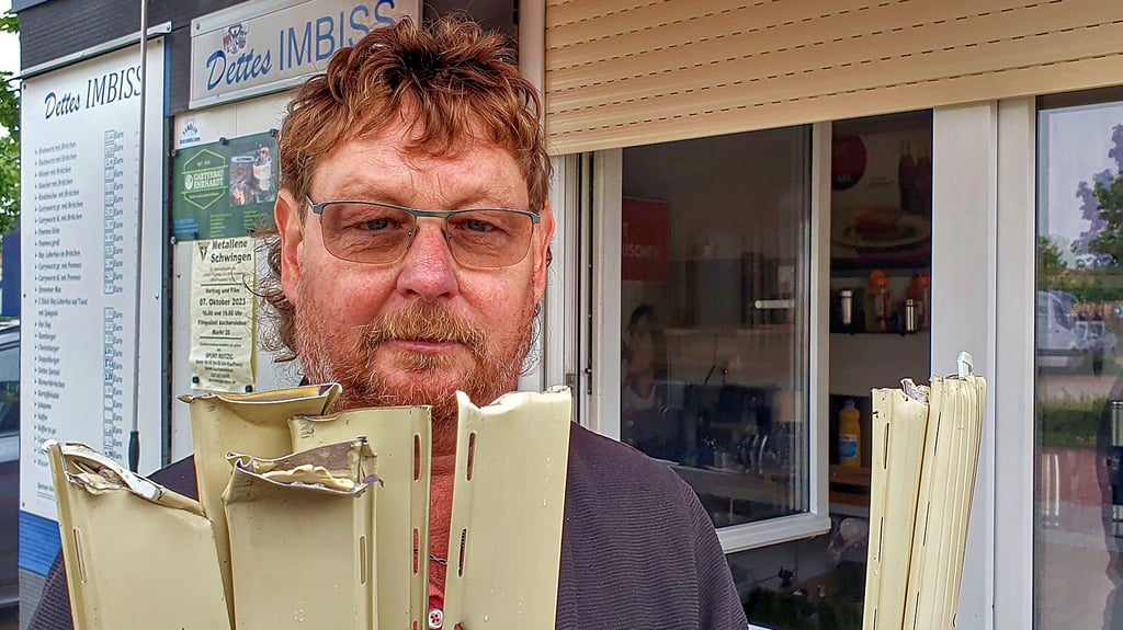 Detlef Ewe zeigt Teile des mit brachialer Gewalt zerstörten Rollladens vor dem Fenster seines Imbissstandes in Aschersleben.