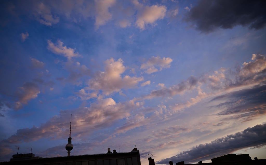 Die Abendsonne erleuchtet Berlins Wolken über dem Fernsehturm rötlich.