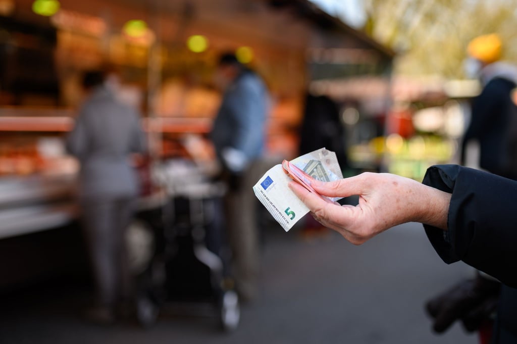 Eine Frau hält das Bargeld für ihren Einkauf in der Hand bereit.