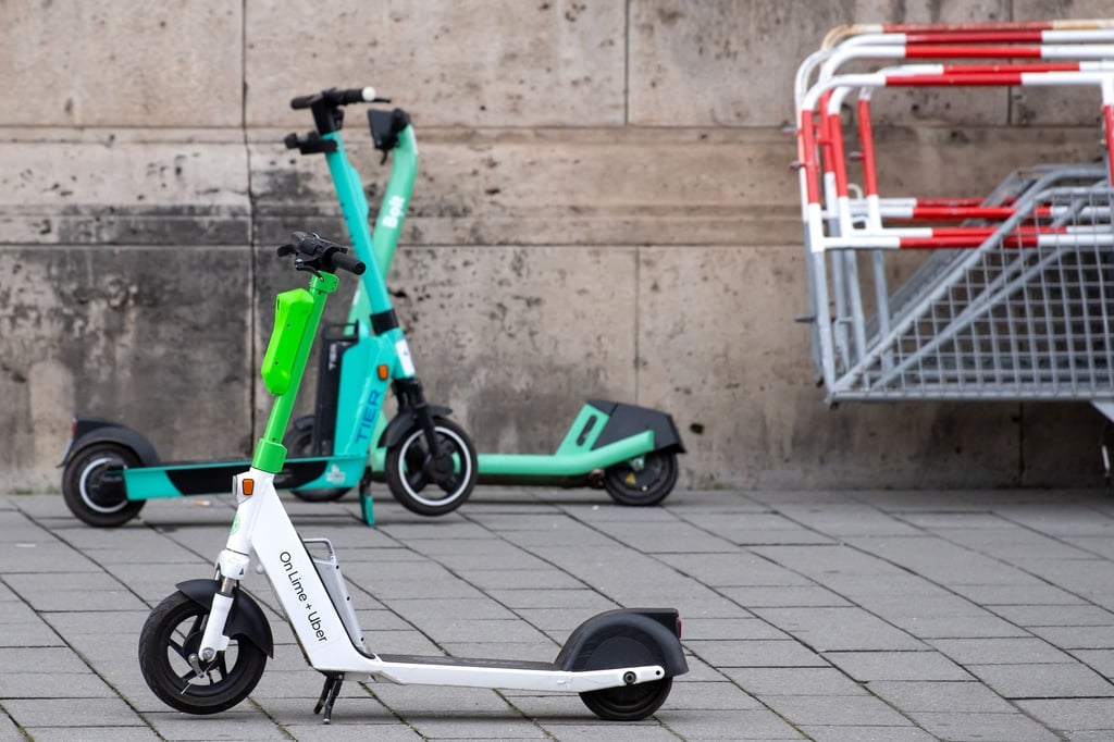 E-Scooter von Lime , Tier und Bolt stehen in der Innenstadt auf einem Gehweg.