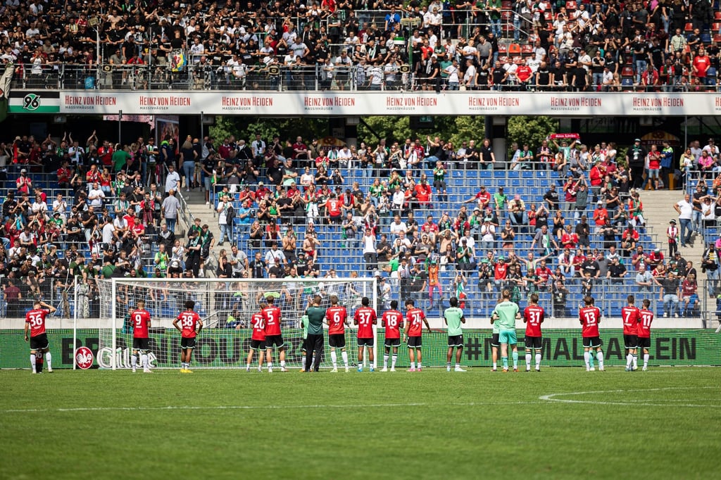 Spieler von Hannover 96 stehen nach Spielende vor der Tribüne mit Fans von Hannover.