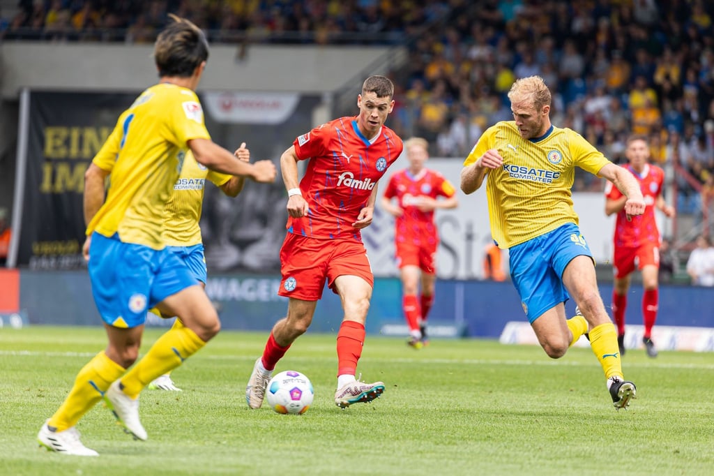 Kiels Philipp Sander (M) in Aktion gegen Braunschweigs Keita Endo (l) und Braunschweigs Sebastian Griesbeck (r).