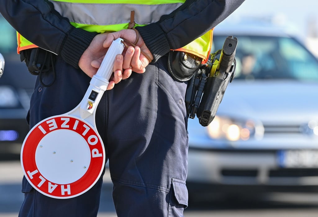 Ein Polizeibeamter hält eine Winkerkelle in den Händen.
