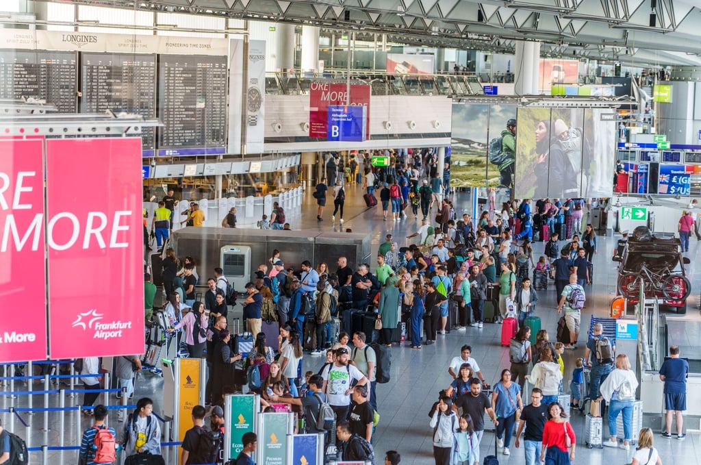 Reisende stehen am Frankfurter Flughafen beim Einchecken in einer langen Schlange.