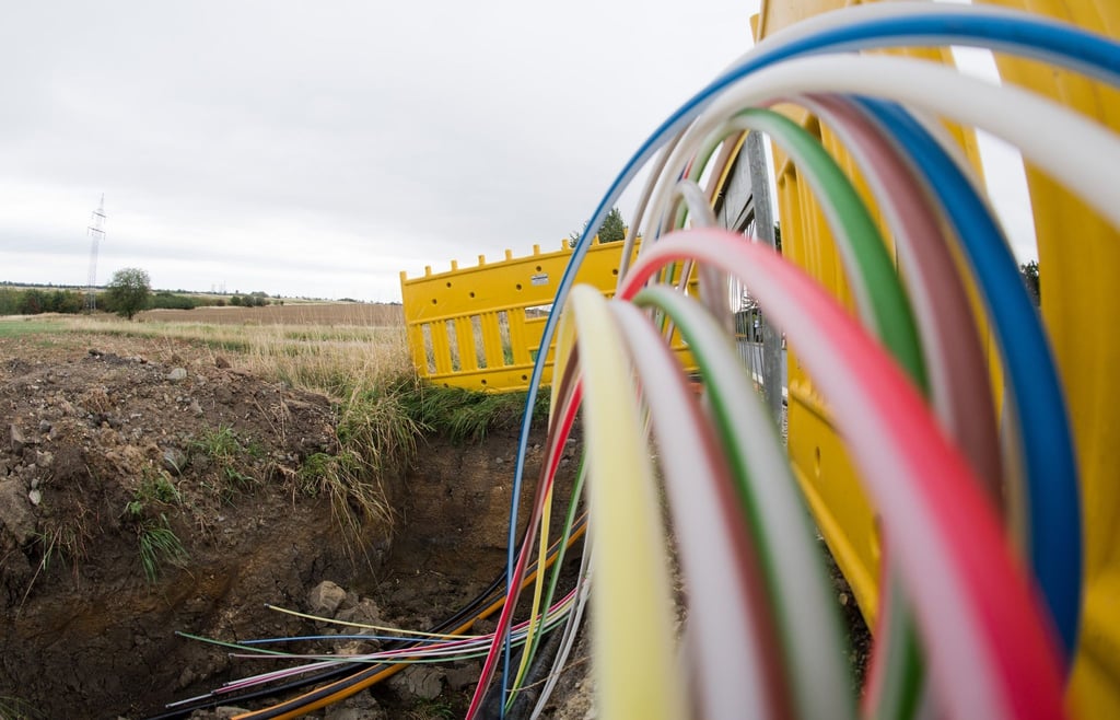 Leerrohre für Glasfaserleitungen für schnelles Internet liegen an einer Landstraße in der Baugrube.