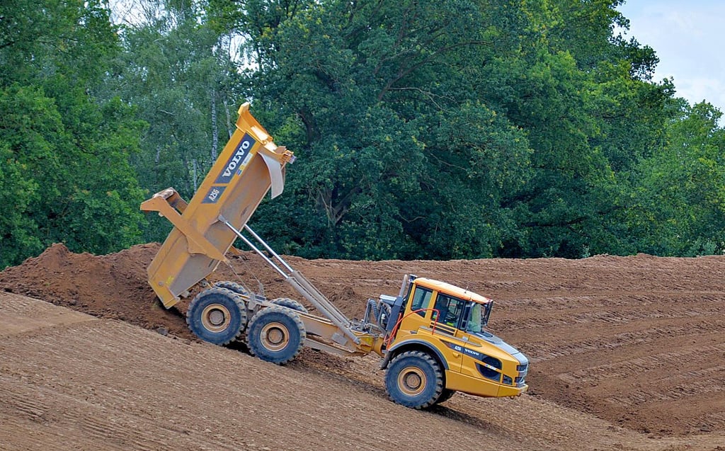 Große Dumper transportieren das Erdreich auf den wasserseitigen Deich, danach wird alles festgewalzt.