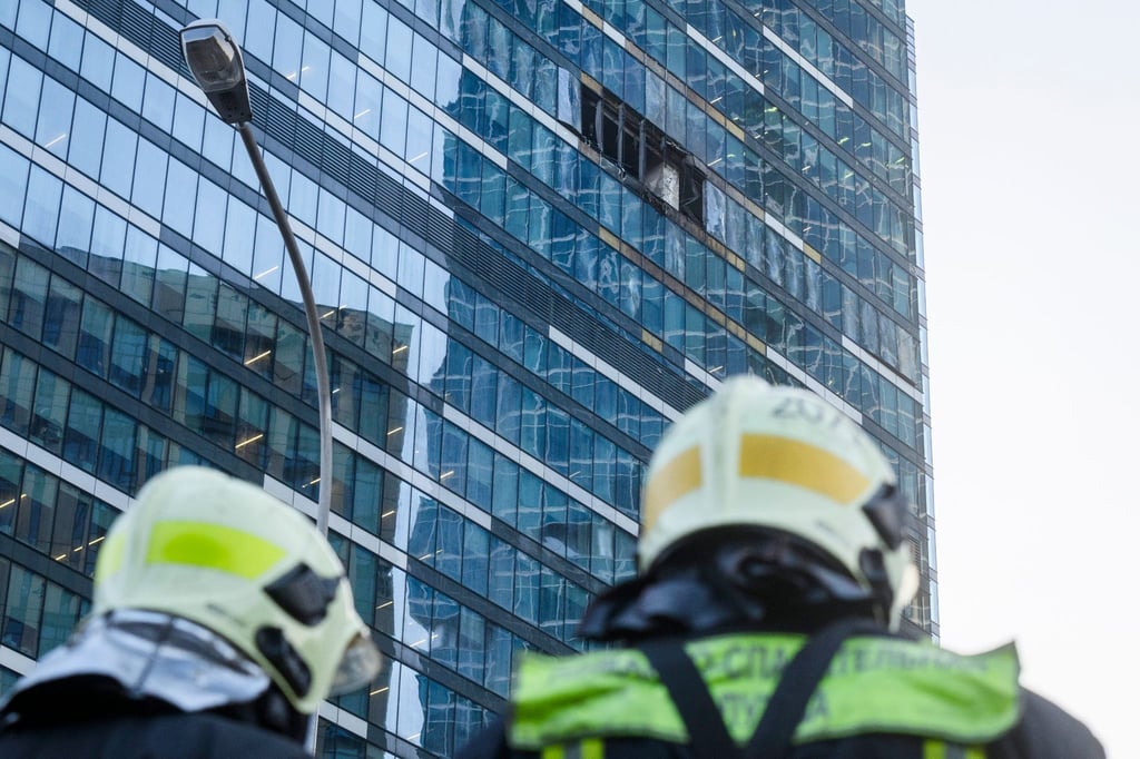 Feuerwehrleute stehen neben dem beschädigten Hochhaus im Geschäftsviertel Moskwa City.