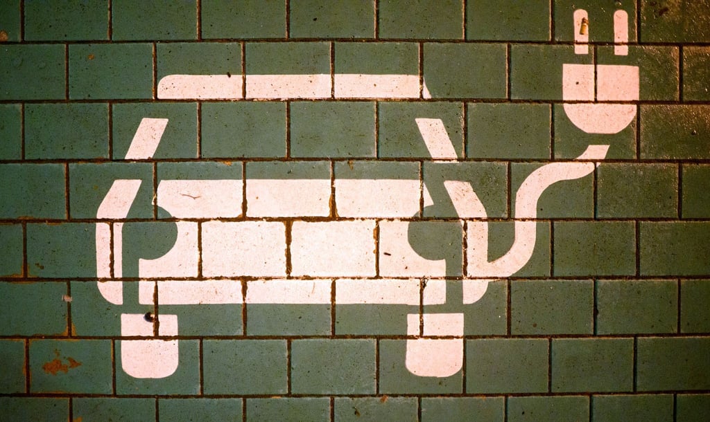 Ein Symbol markiert einen Parkplatz mit einer öffentlichen Ladesäule für Elektroautos.