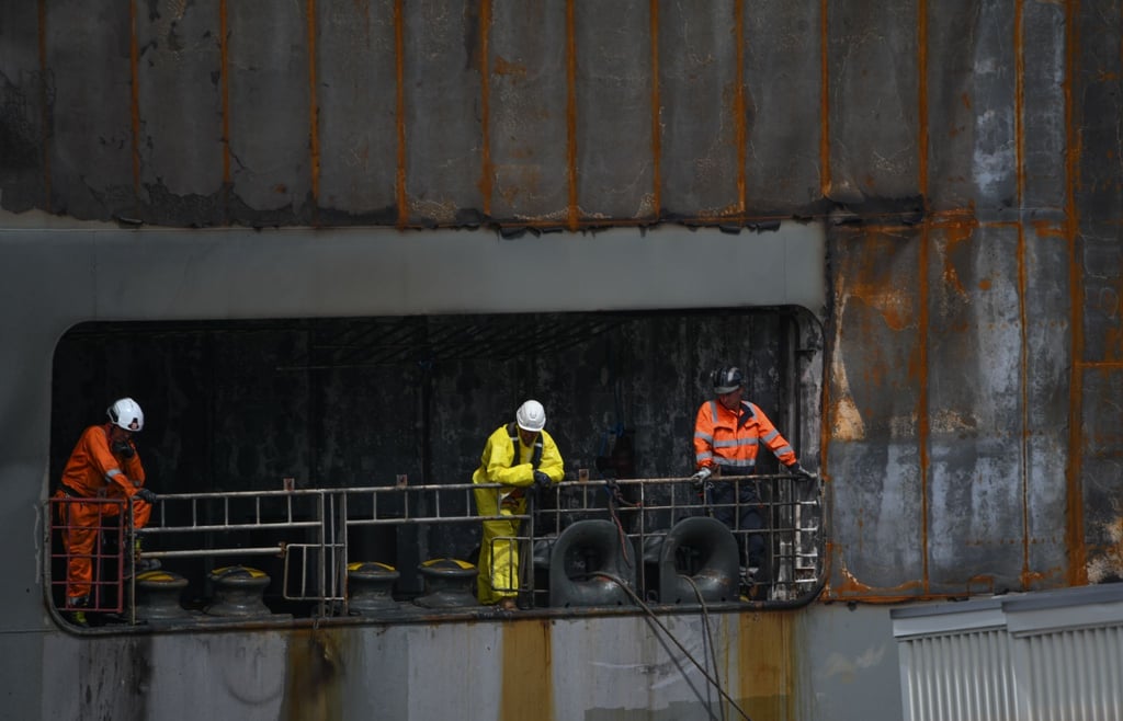 Arbeiter beaufsichten an Bord des schwer beschädigten Autofrachters “Fremantle Highway„ das Anlegemanöver im Hafen.