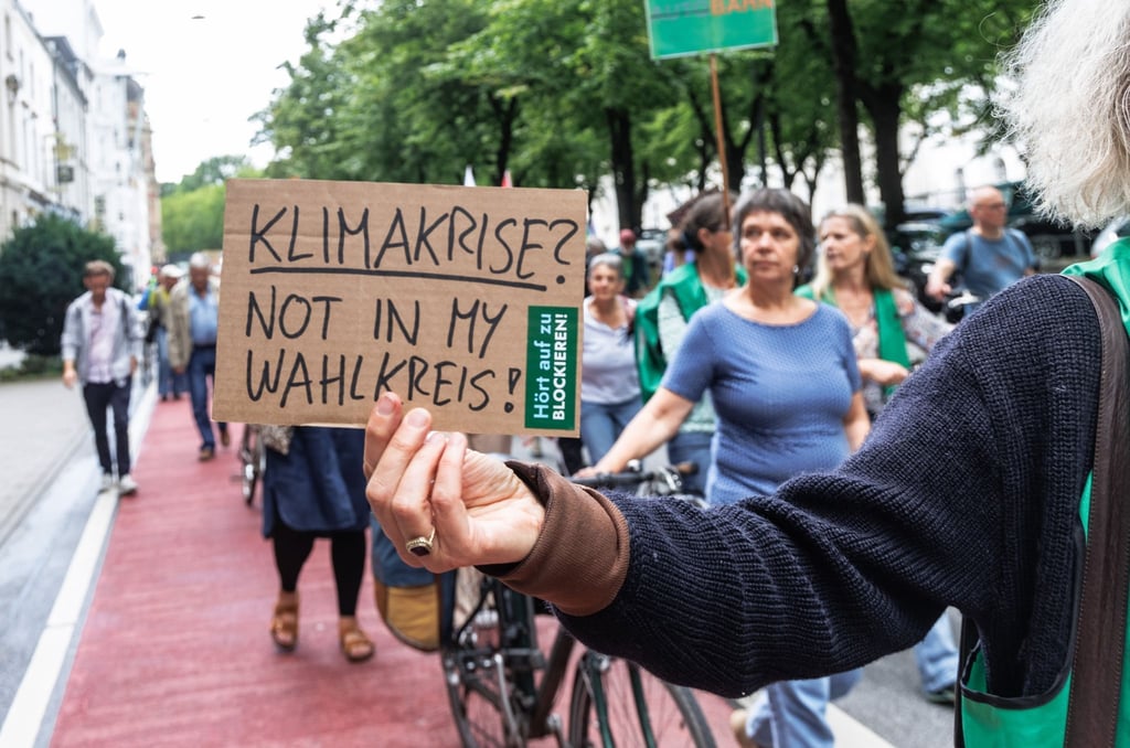 Eine Demonstrantin hält ein Schild mit der Aufschrift „Klimakrise? Not in my Wahlkreis!“.