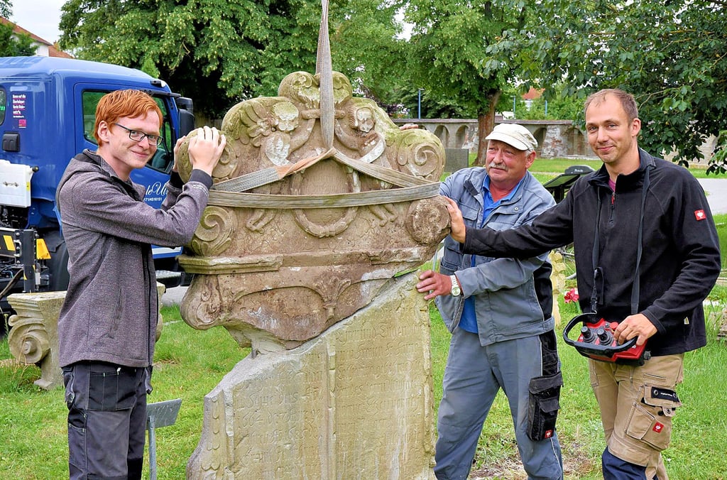 Schüler Jeremy-Pascal Haberkorn (von links), Geselle Michael Hamann und Steinmetzmeister Eike Ulrich setzen einen barocken Grabstein zusammen, der bei Wegebauarbeiten gefunden wurde.
