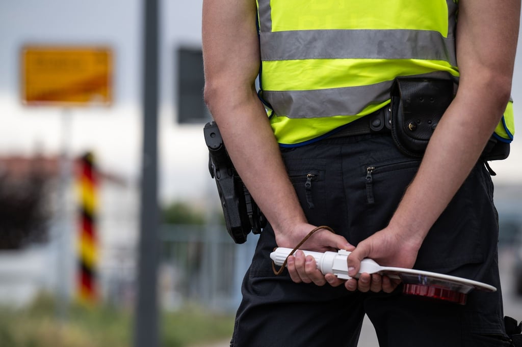 Ein Polizist mit Haltekelle in den Händen steht an der deutsch-polnischen Grenze.